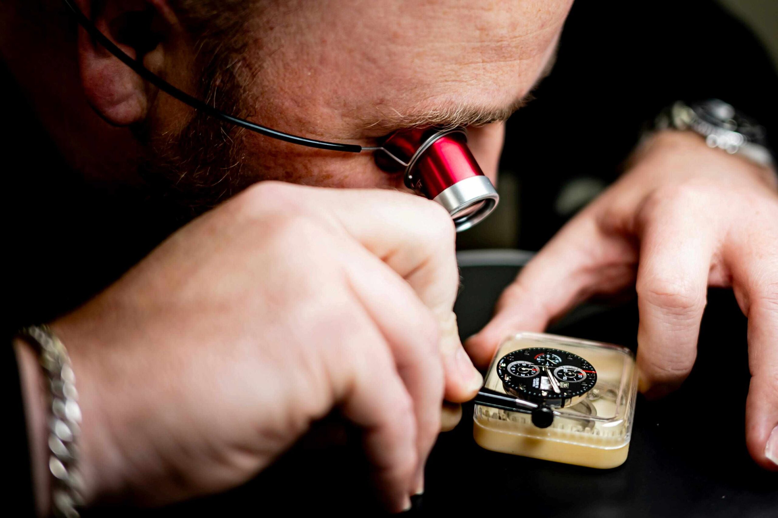 Zegarmistrz patrzący przez lupę zegarmistrzowską na mechanizm zegarka